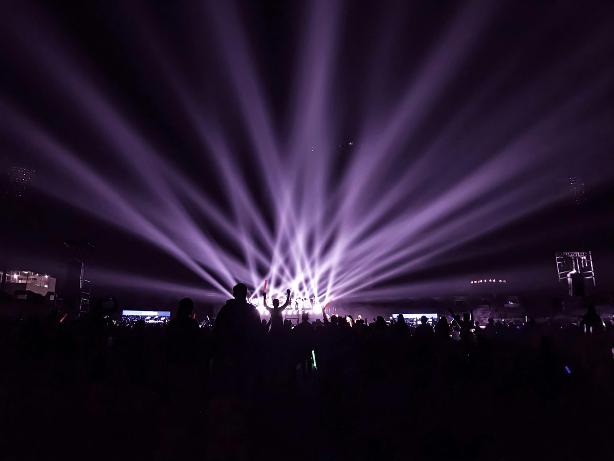 Purple stage lights over a festival crowd